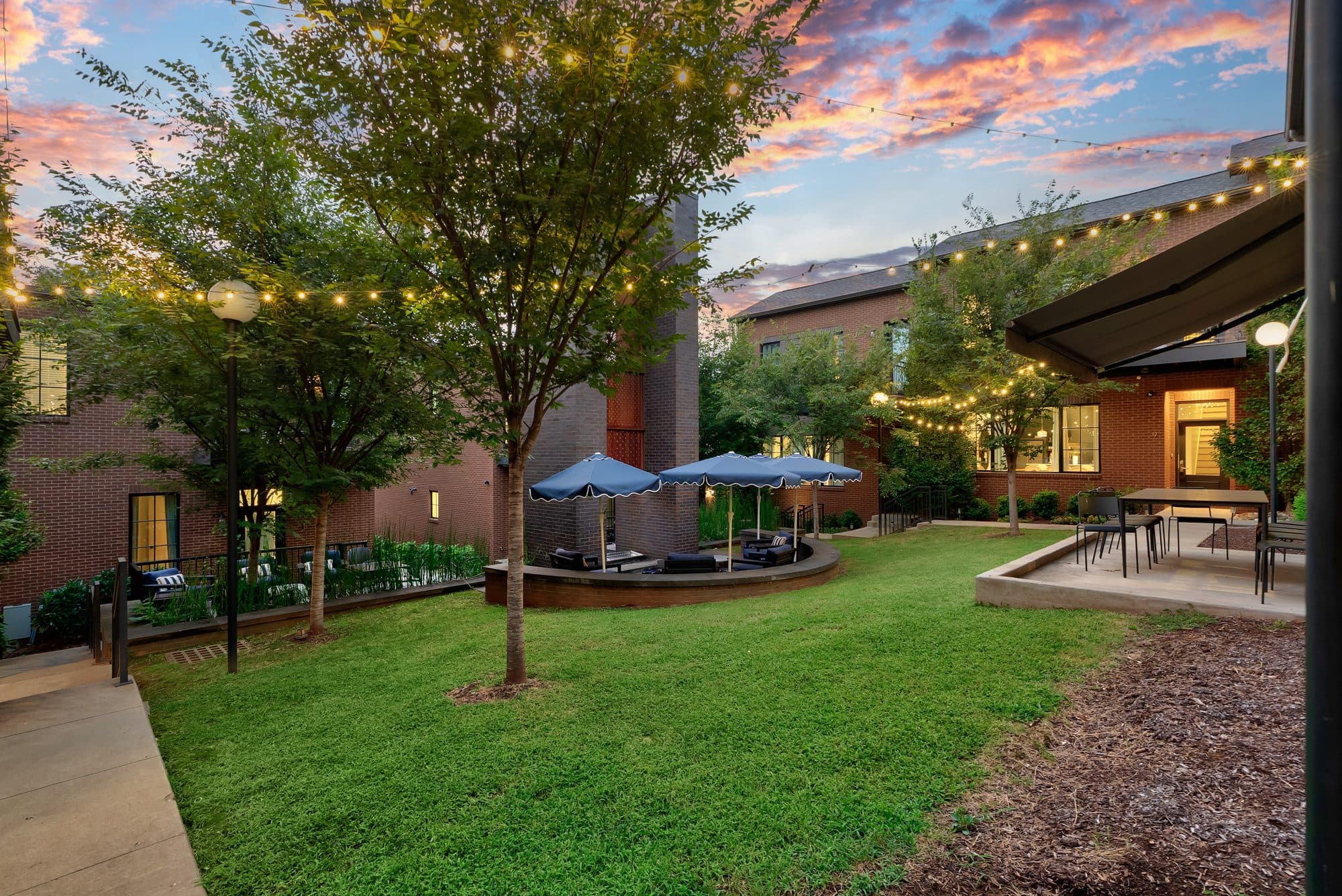 The Magnolia courtyard lawn under string lights at twilight